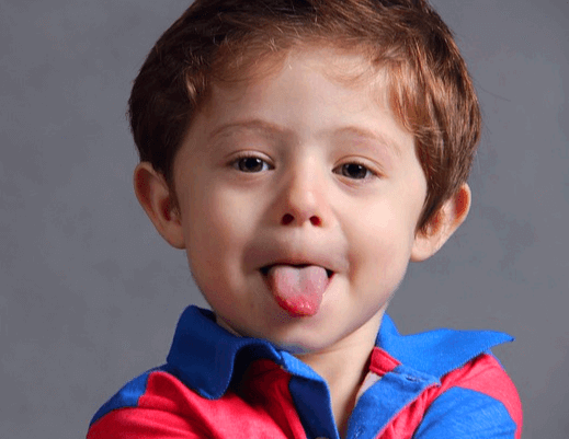 갈색머리 남자 백인 아이가 혀를 길게 쭉 내밀고 정면을 바라보고 있다.