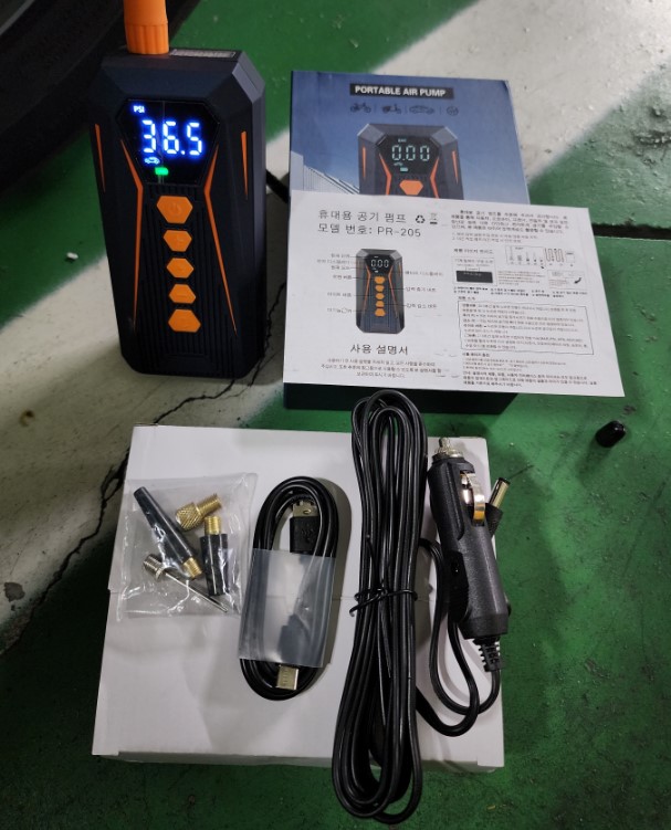 휴대용 공기압 주입기와 설명서, 충전 케이블, 시거잭 연결 케이블, 어댑터를 펼쳐 놓은 모습