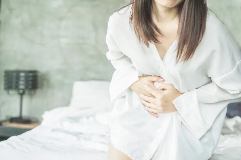 사후피임약 부작용을 나타내는 두통과 복통을 겪는 여성 사진입니다.