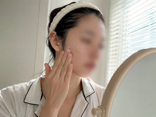 화장대 거울 앞에서 세안 후 건조해진 피부에 촉촉한 수분 크림을 부드럽게 펴 바르고 있는 모습
