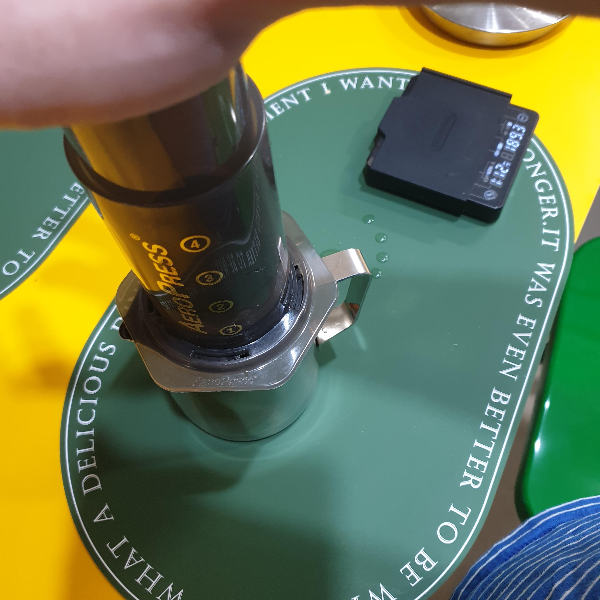 스팀피처 위에 올라간 에어로프레스에 손을 올려 누르고 있다.