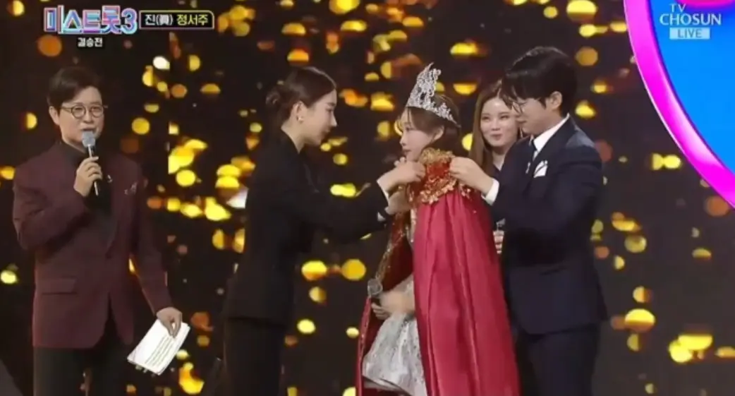 미스트롯3- 검은색 금빛 꽃이 내리는 배경 정서주에게 여왕가운을 입혀주는 여자와 남자