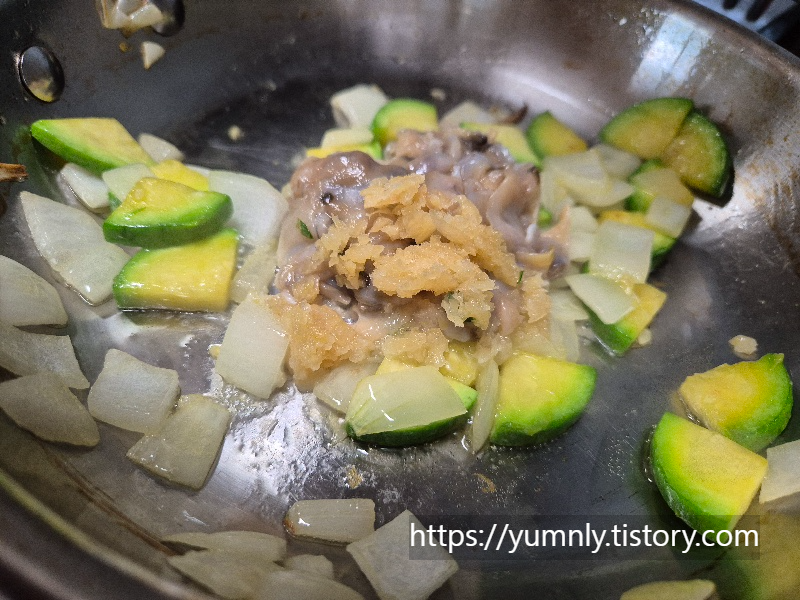 Adding fresh clam meat and minced garlic to the sautéed vegetables with a splash of white wine.