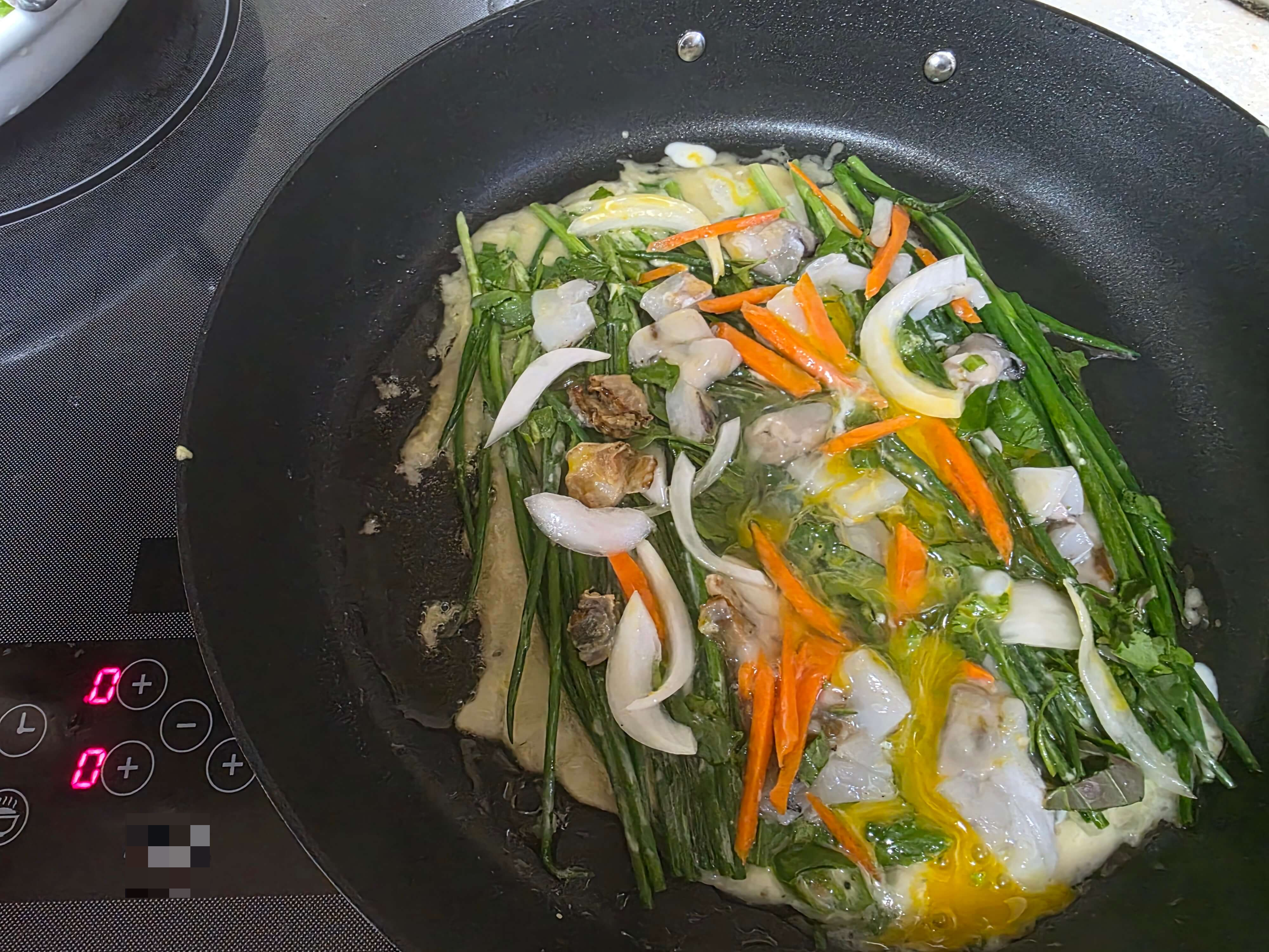 프라이팬 위에서 조개살 파전이 노릇하게 익어가는 모습