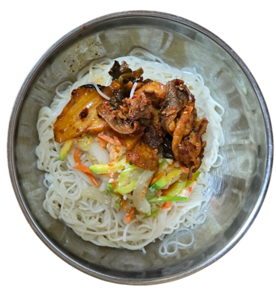 그릇에 잘 삶아진 소면이 담겨 있고, 그 위에 볶은 대패삼겹살과 묵은지, 채소가 올려진 모습 (육수 붓기 전)