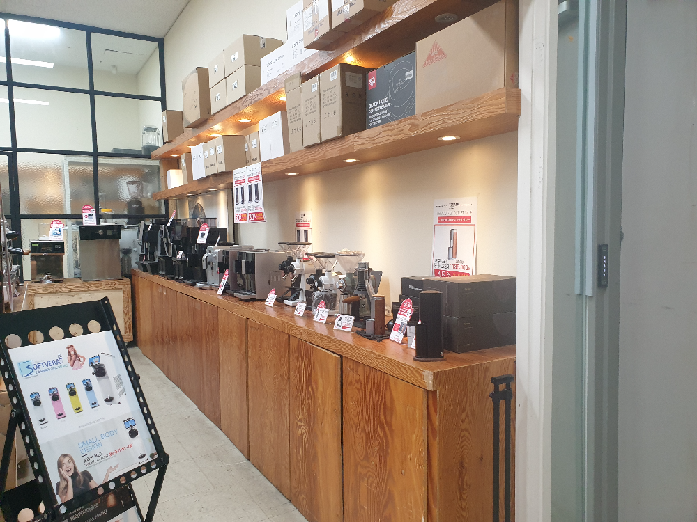 우드 장 위에 전자동 머신과 그라인더들이 올려져 있다.