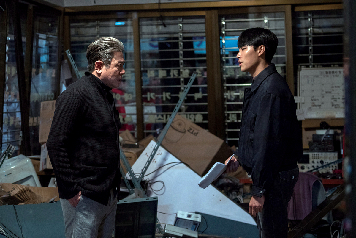 어두운 방 안에서 주인공과 한 남성이 서로 마주 서 있는 장면, 영화 침묵 스틸컷