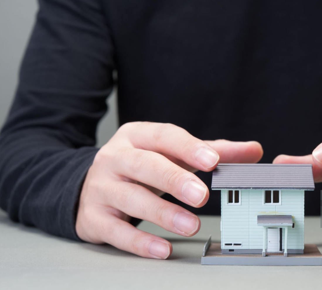 남자가 집 모형을 손으로 잡으려 하는 사진