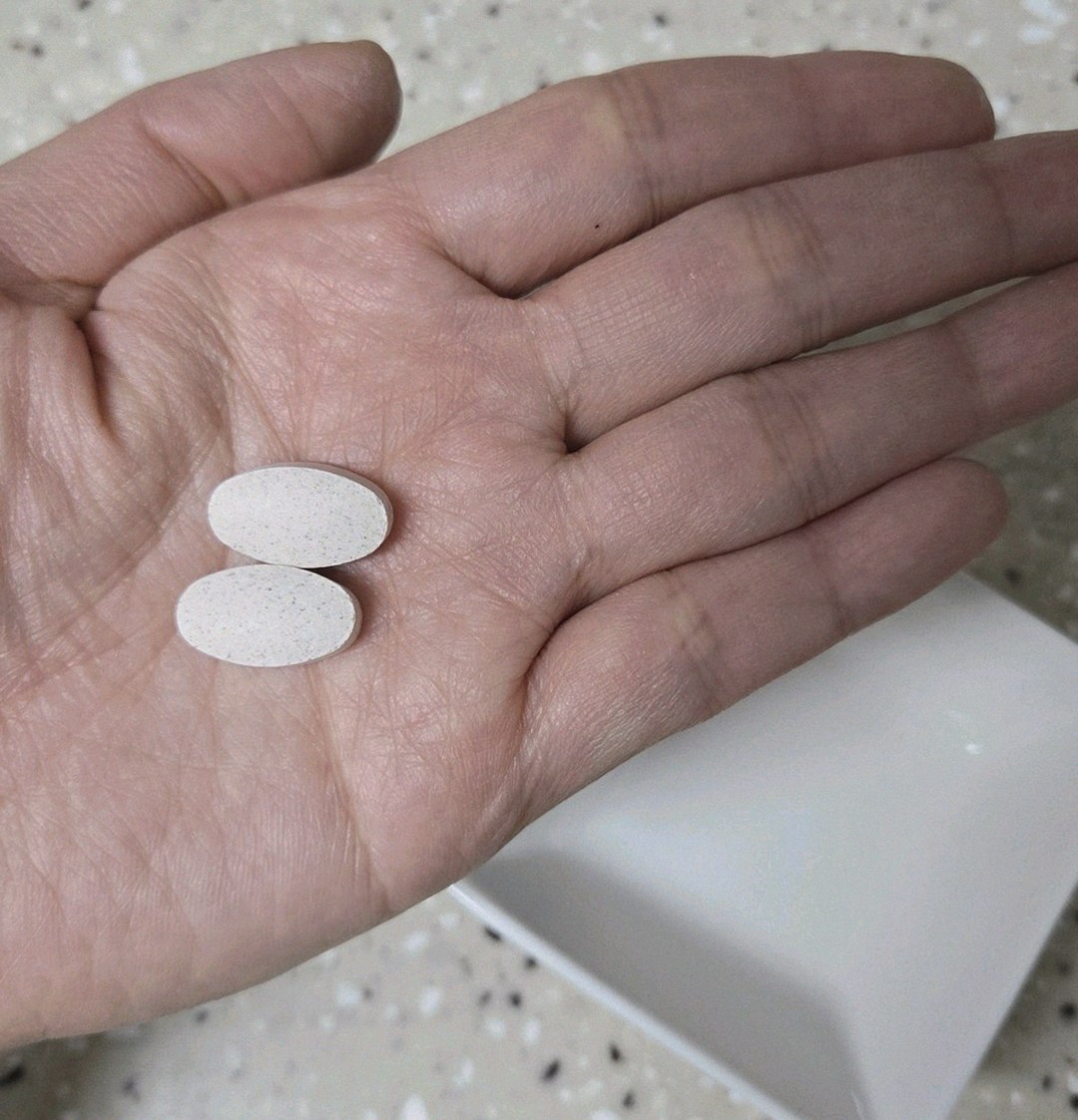 Korean Asian man in 40s holding supplement bottle in morning kitchen