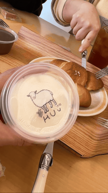 분당 미금역 카페 휴유에서 구입한 푸딩을 손으로 보여주는 gif. 뒤에서는 동생이 소금빵을 포크와 나이프로 자르고 있다.