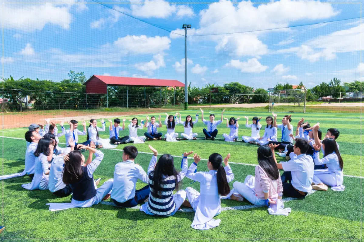 잔디밭에 학생들이 동그랗게 앉아 웃는 모습
