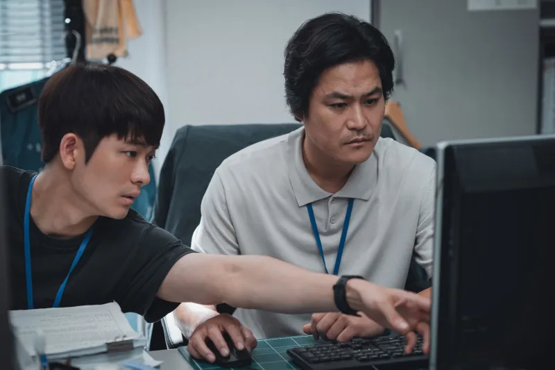 경찰서 책상 앞에 모니터를 바라보고 있는 영화 타겟의 주형사와 나형사