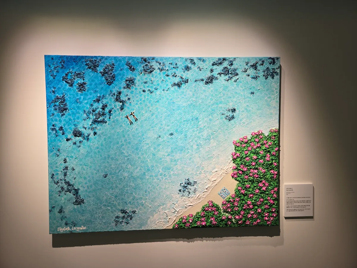 붉은-꽃이-해변을-따라-펼쳐져-있고-푸르른-바다-위헤-두-남녀가-바다를-즐기고-있는-그림