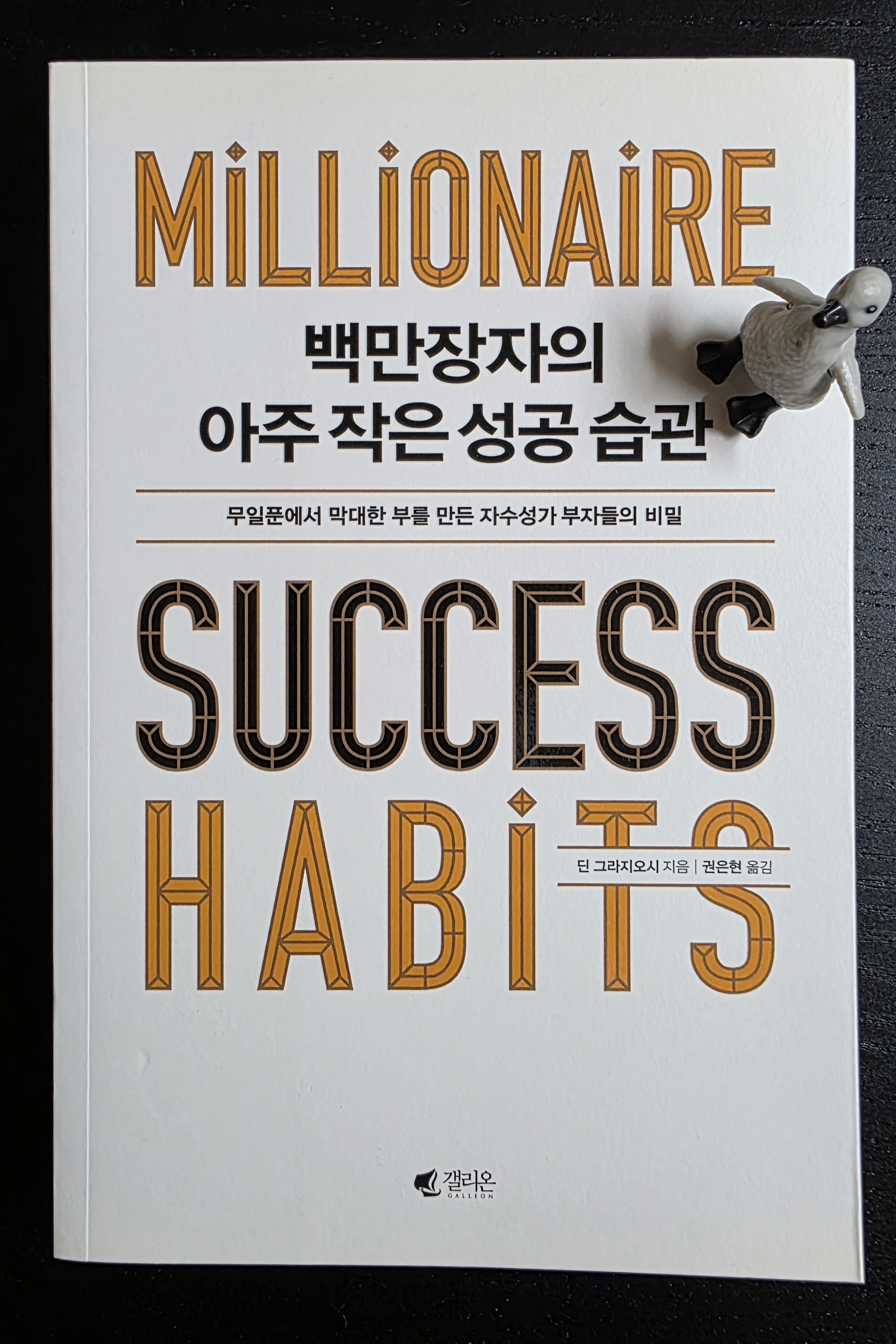 펭귄 피규어가 올려진 백만장자의 아주 작은 성공 습관 책 표지