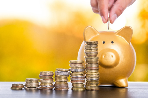 쌓여있는 동전들과 돼지저금통에 동전을 넣는 모습