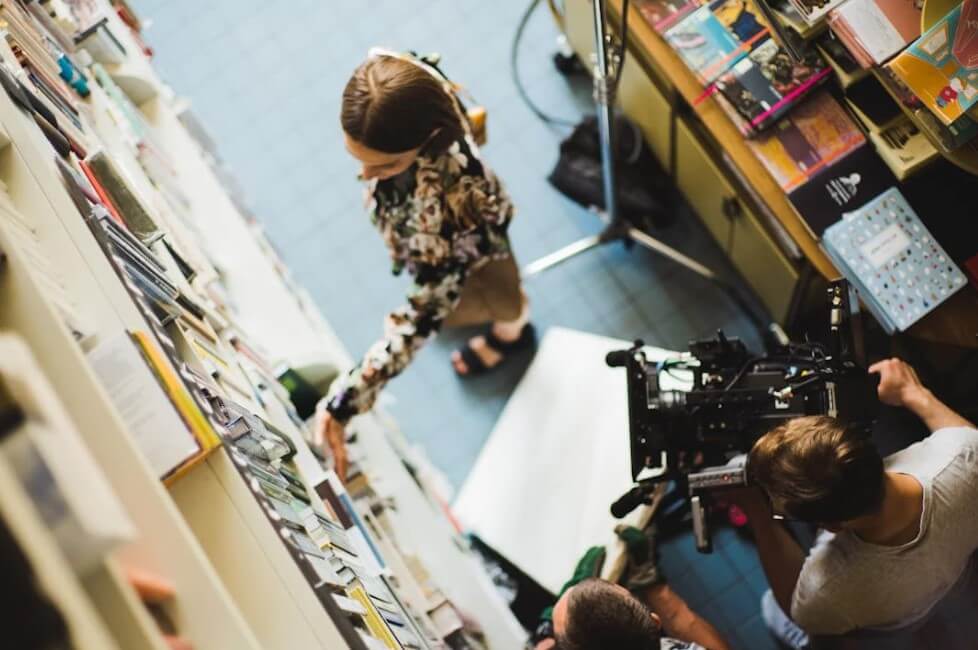 책장 앞에서 촬영 중인 영화 현장. 실제 영화 촬영지의 분위기를 보여주는 장면입니다.