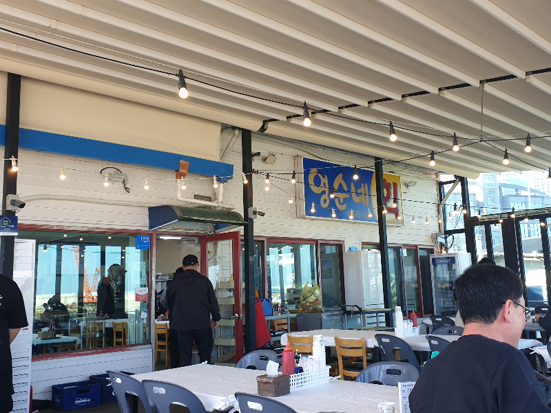 손님 한 명이 보이고 직원들이 일하고 있다. 큰 창들이 보인다.