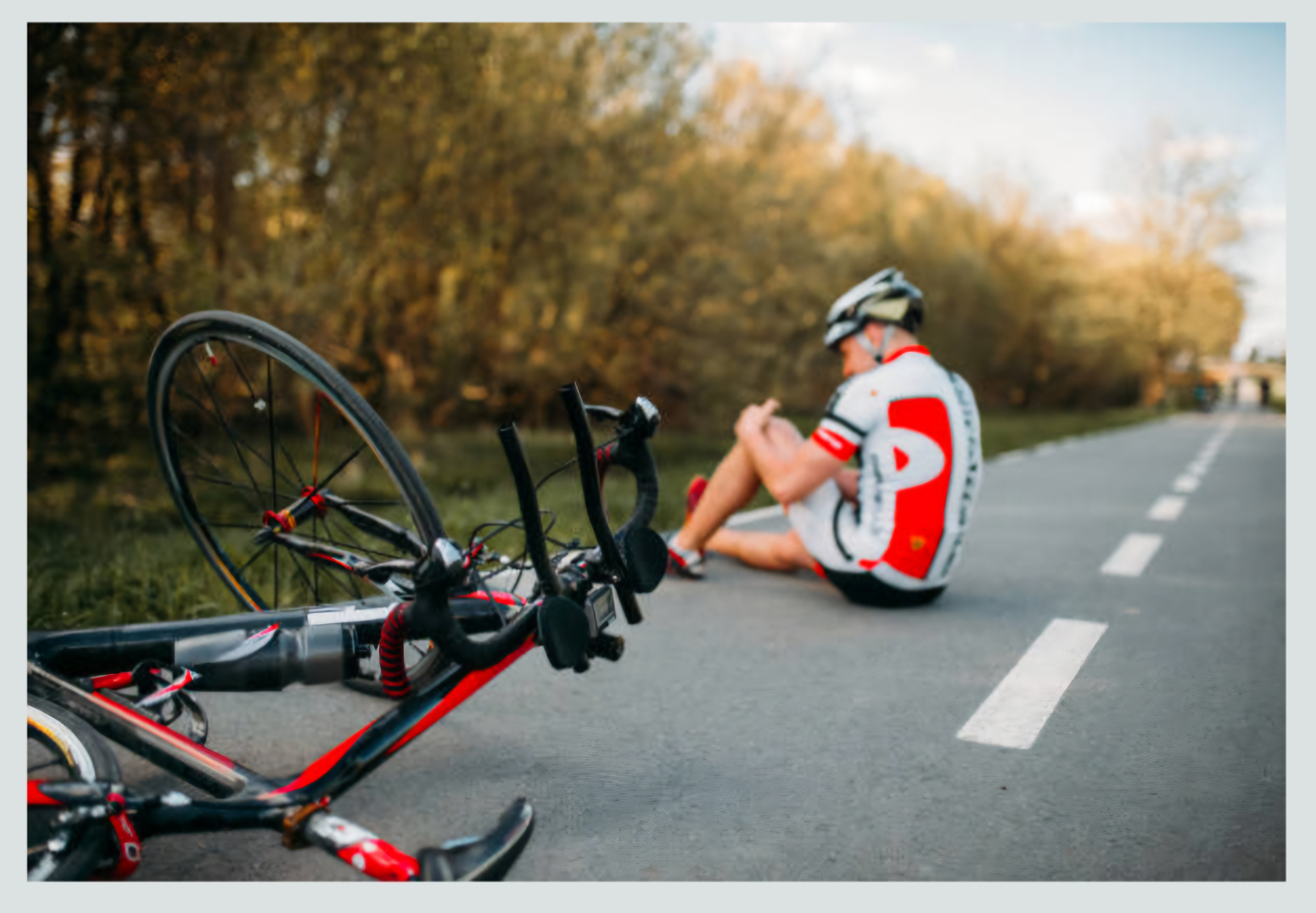 쓰러져있는 자전거와 그 뒤로 무릎을 움켜쥔 선수