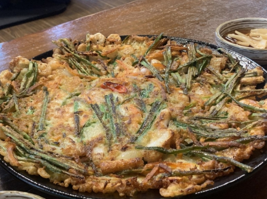 쪽파와 고추, 새우 등과 밀가루를 혼합하여 부친 파전을 동그랗고 검은 접시에 한가득 담아놓고 확대를 하여 찍은 사진