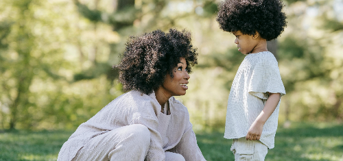 엄마가 아이의 눈높이를 맞추기 위해 앉아 바라보고 있는 장면