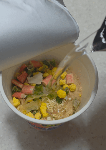 일본 닛신 컵누들 씨푸드맛에 뜨거운 물을 붓는 모습
