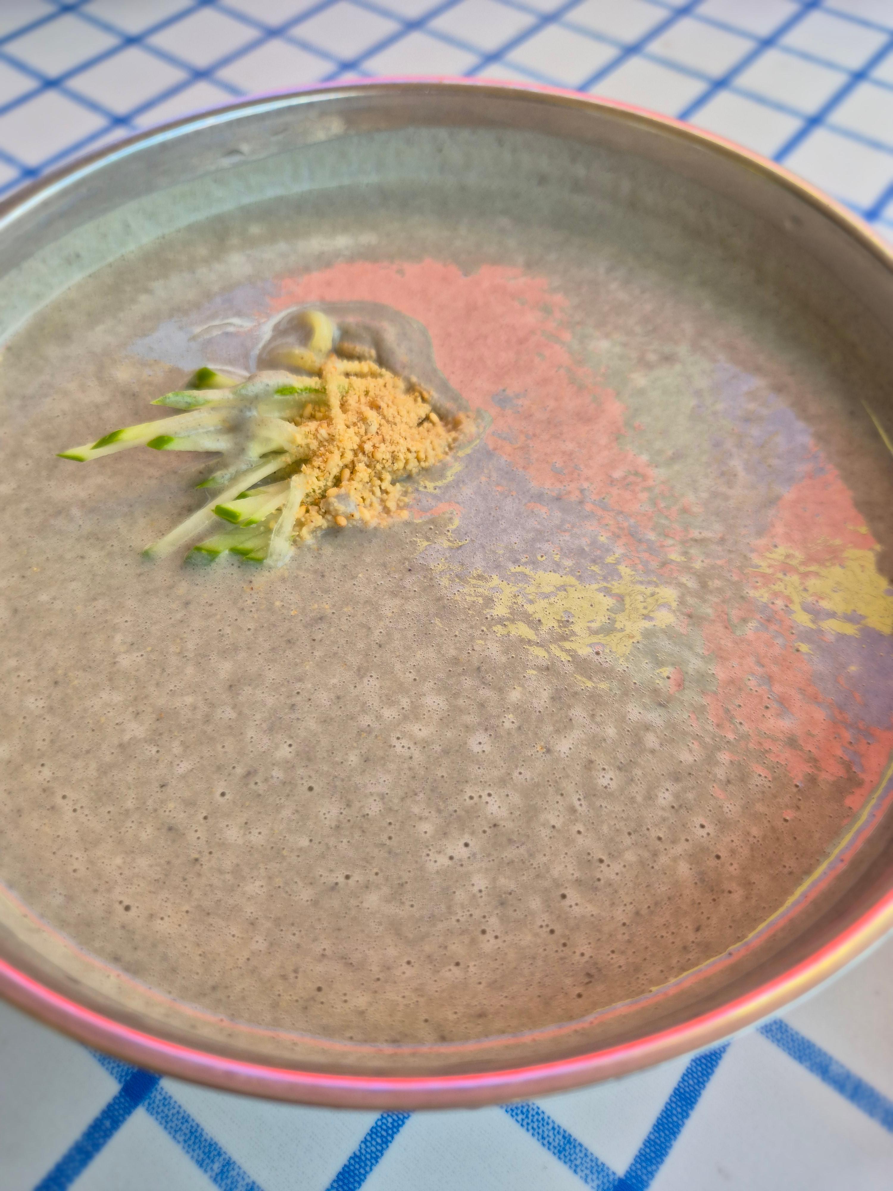 검은콩 빛깔의 걸쭉한 콩물에 면과 오이 고명이 담긴 면천 콩국수