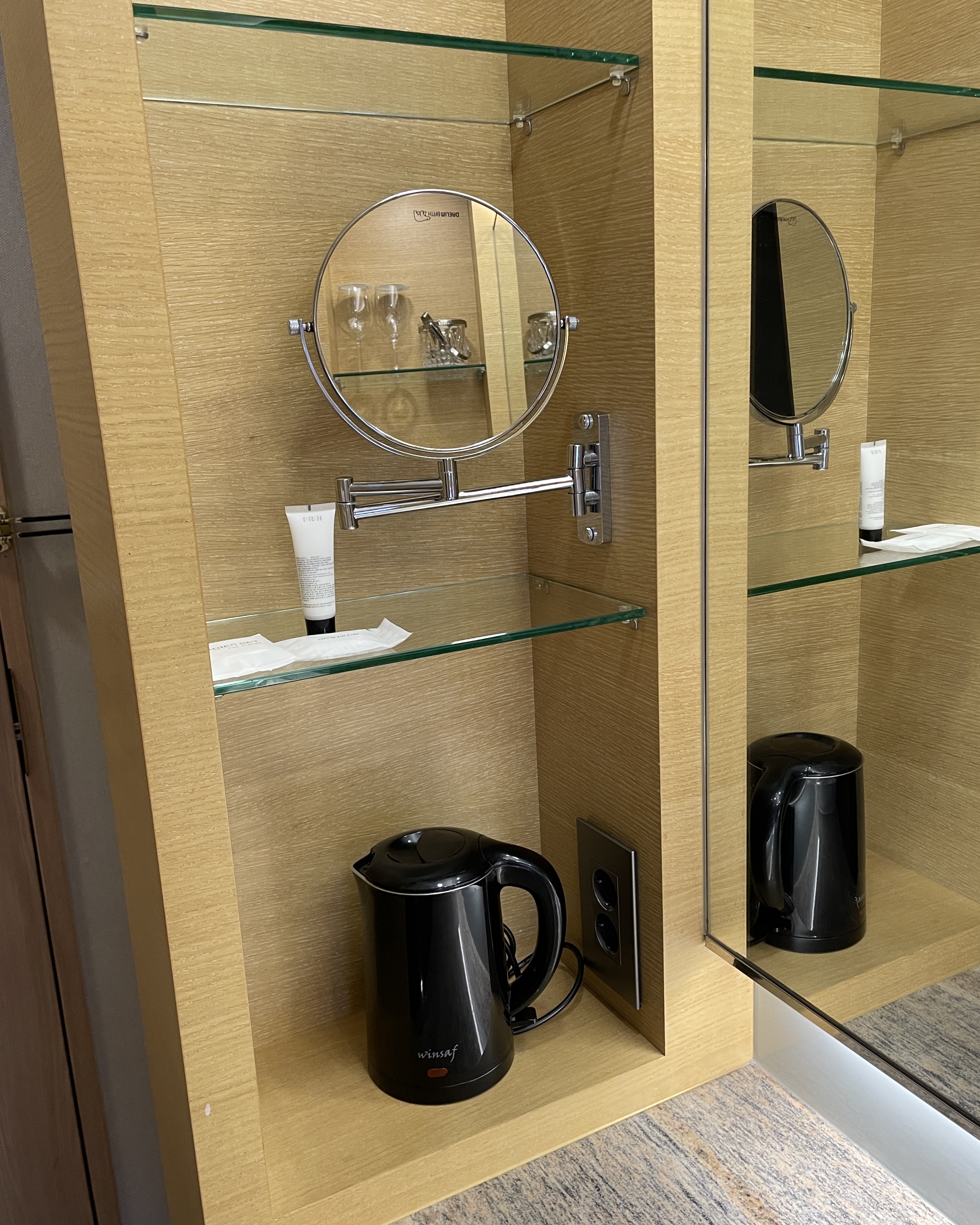 세면대 왼쪽 모습. 작은 거울, 세면 용품, 커피포트가 있다.