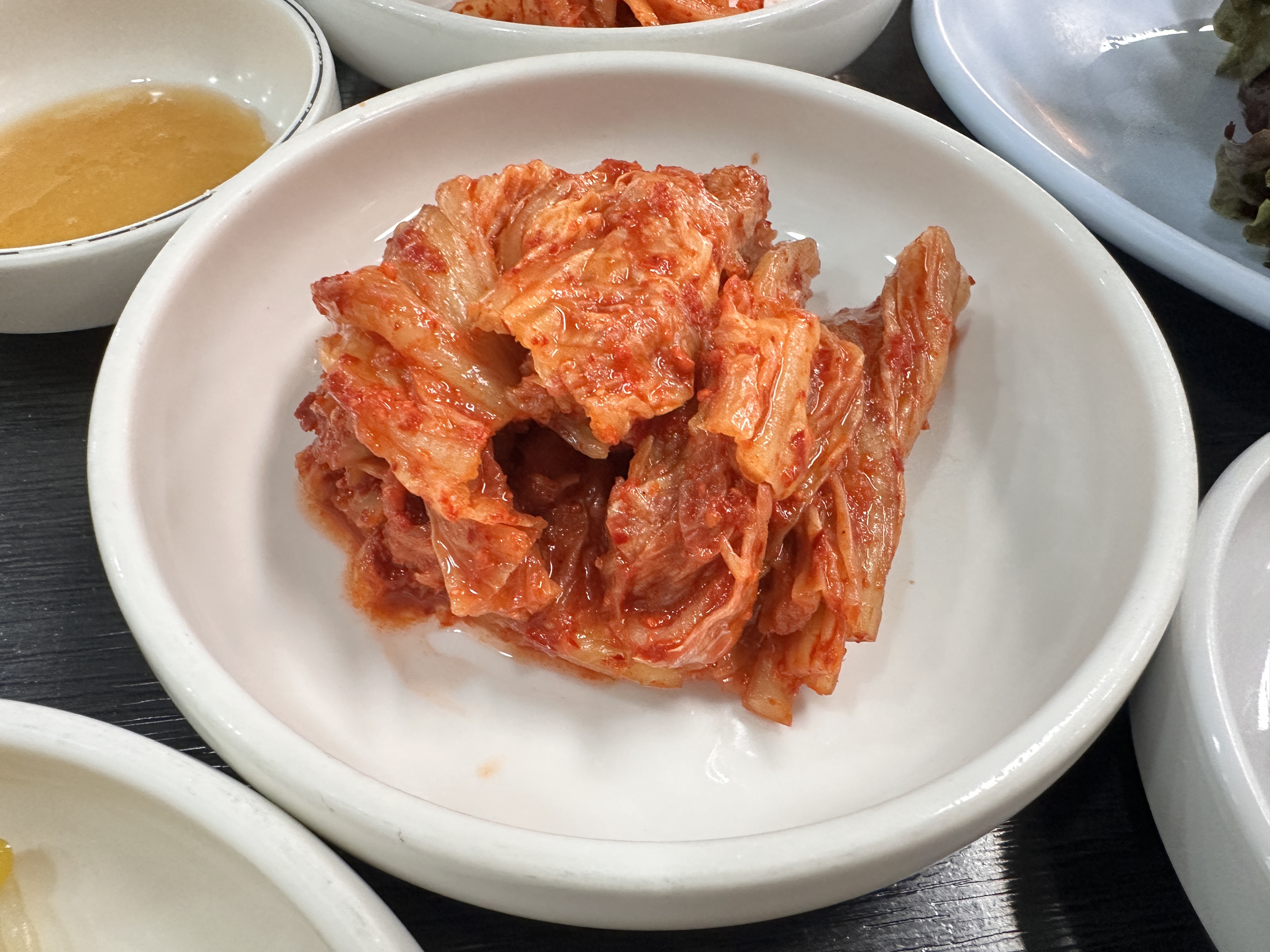 하얀 작은 접시에 담긴, 고춧가루 양념이 잘 버무려진 배추김치 클로즈업
