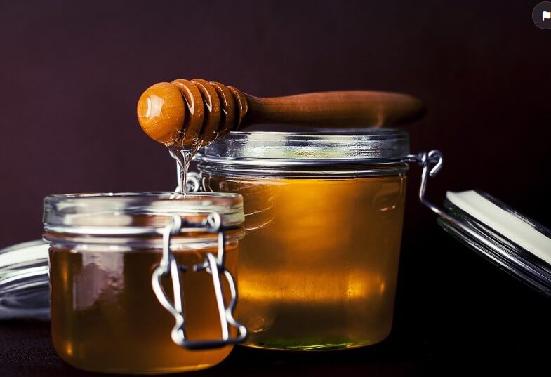 마누카-꿀이-들어-있는-단지와-나무-스푼에-듬뿍-묻어-있는-사진입니다.