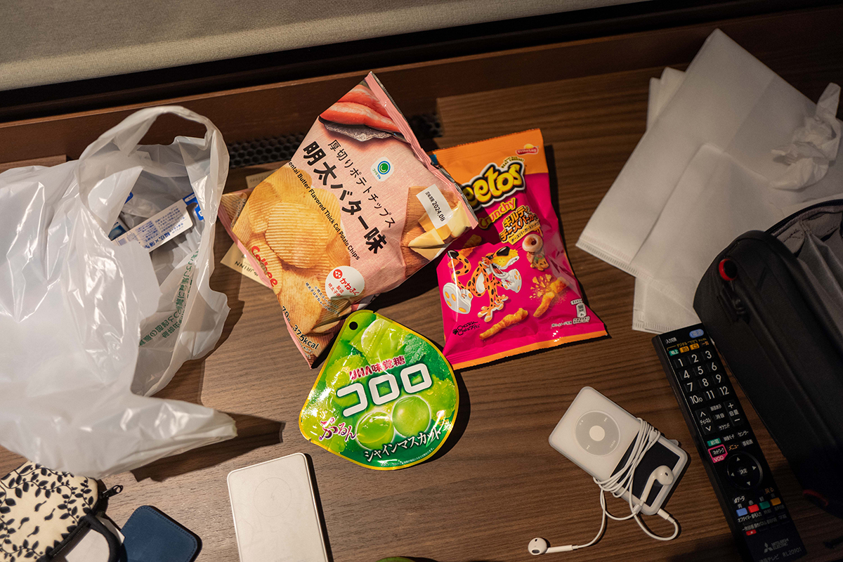 테이블 위에 과자와 각종 소품들이 올라와 있는 모습. 사진의 가운데 과자가 있고 주변에 차마 정리하지 못한 비닐봉투, 리모컨 등이 함께 올려져 있다.