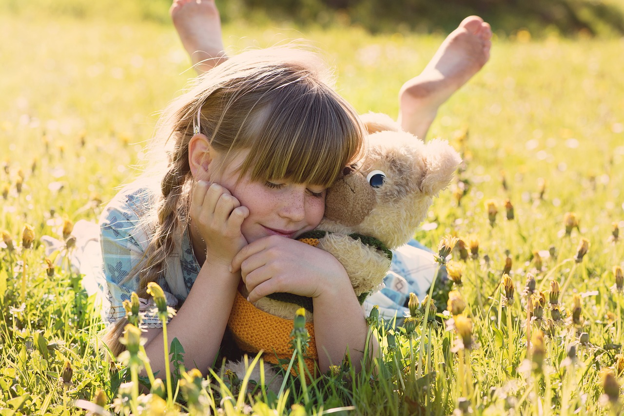 a girl holding a teddy bear and smiling with satisfaction