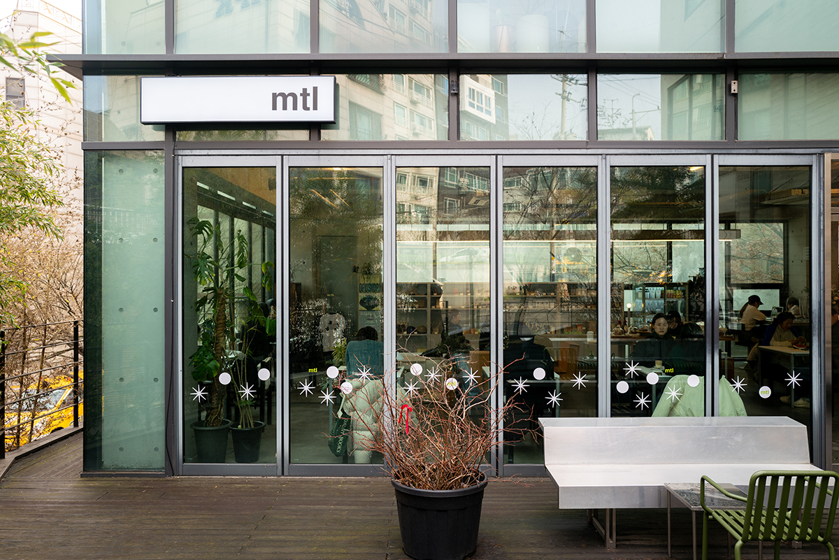 라이카 Q2의 28mm 주미룩스 렌즈로 촬영한 mtl 카페 외관 전경. 유리창의 반사와 건물의 디테일이 선명하게 표현된 고화소 사진.