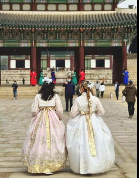 한복을-입은-여자-둘이-경복궁을-거닐고-있습니다,