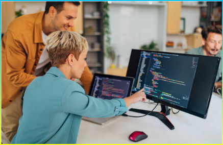 는 남성 프로그래머가 사무실의 책상에 앉아있는 동안 새로운 여성 동료에게 코딩 기술을 설명