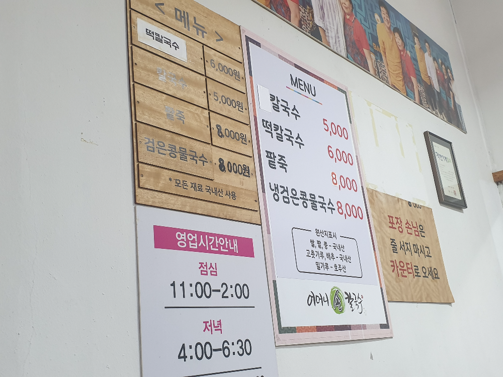 벽에 메뉴판 및 영업 시간 안내 표지판들이 붙어 있다.