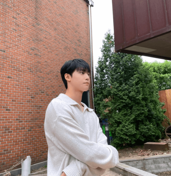 배우-이도현이-벽돌-건물-옆에서-흰카라티를-입고-오른쪽을-응시하고-있는-장면