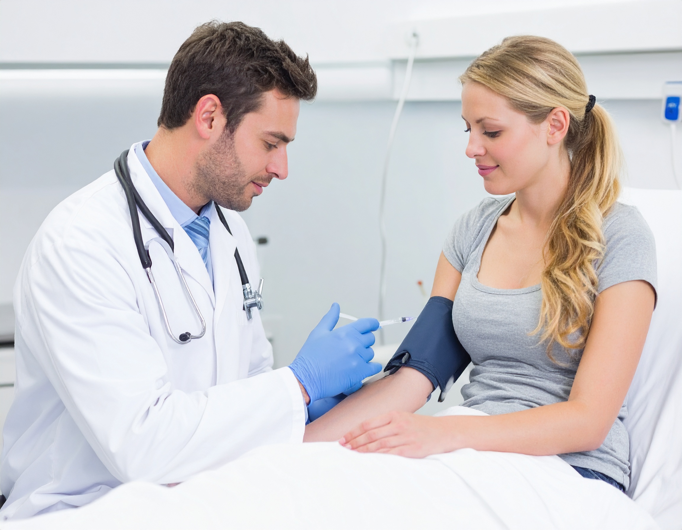 건강검진 중 혈압 측정을 받고 있는 젊은 여성의 모습. 남성 의사가 혈압 커프를 착용하고 설명하는 장면