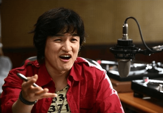 영화-속-장면으로-박중훈이-빨간-셔츠를-입고-오른손에-펜을-든-채-말을-하고-있는-사진