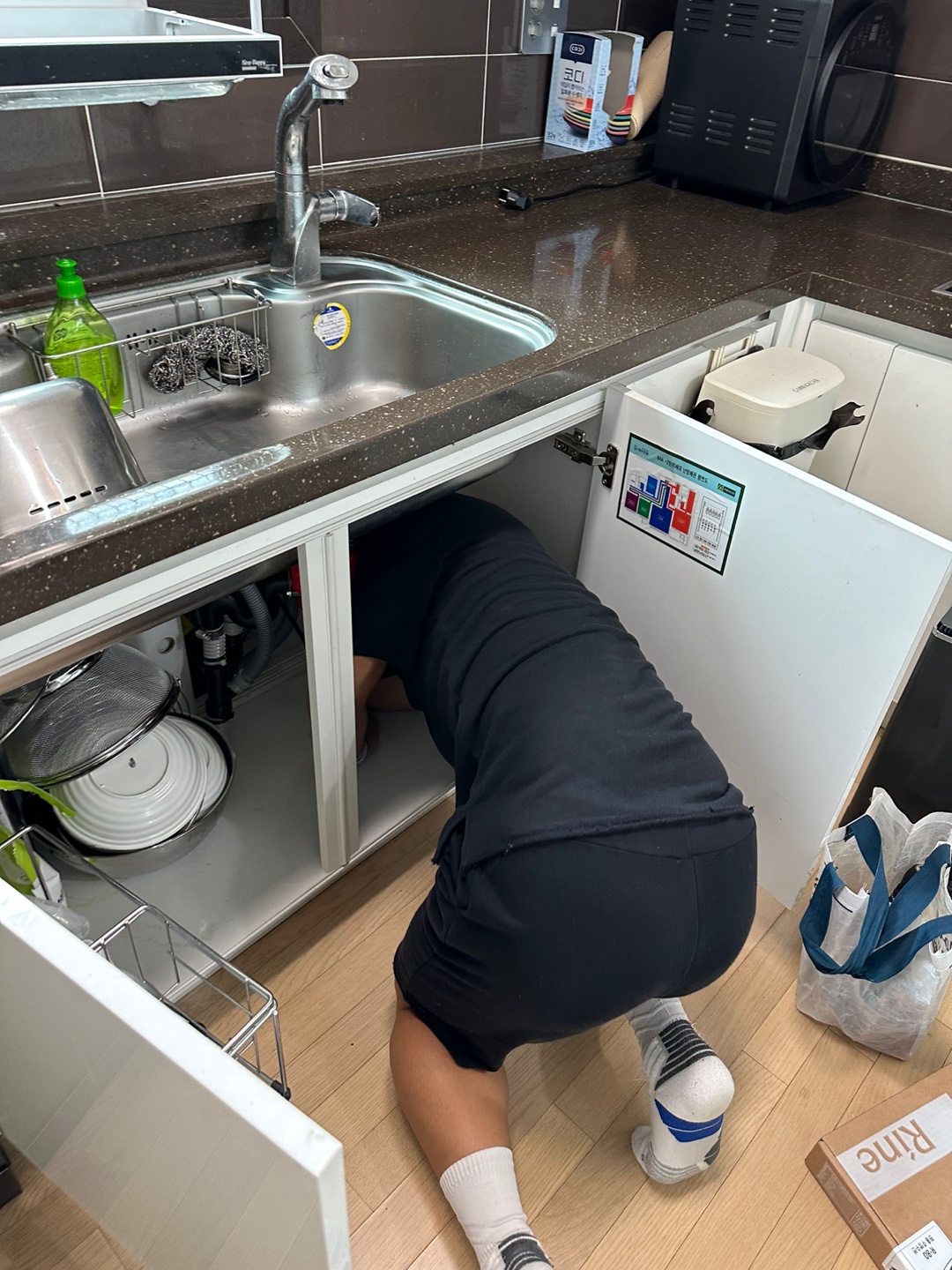 싱크대 하부장 안에서 좁은 공간에 몸을 구부려 수전교체 작업을 하는 야무진 집수리전문가