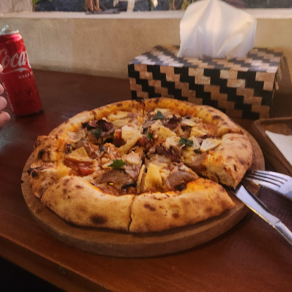 주문한 피자. 6조각으로 잘려있다. 포크와 나이프는 하나씩 보인다. 옆에 콜라도 있다.