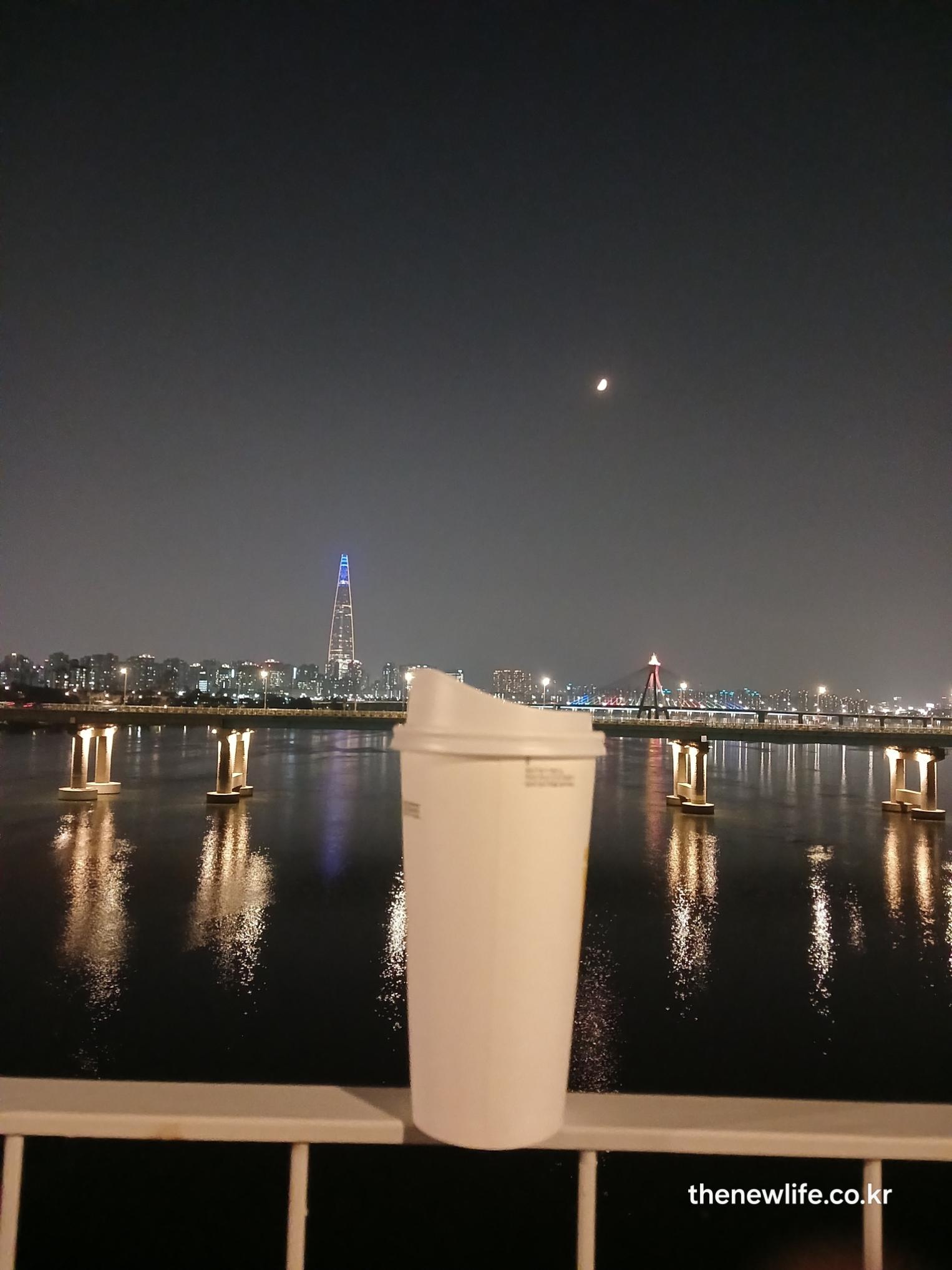 밤 한강 다리 불빛과 롯데타워를 배경으로 한 잔의 블랙커피