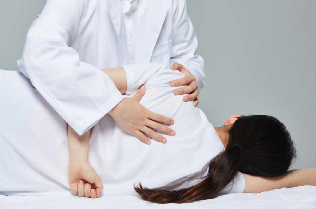 한 여성이 옆으로 누워 물리치료를 받고 있다.