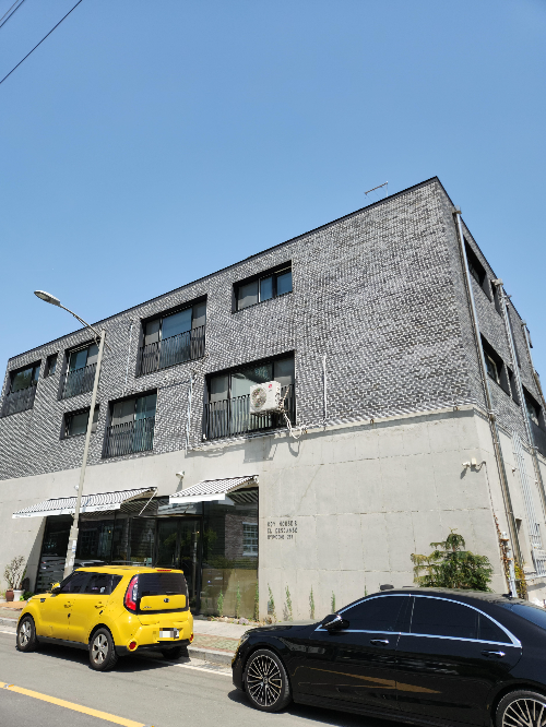 카페 엘데스칸소 콘크리트 건물 앞에 노란 차가 서 있다