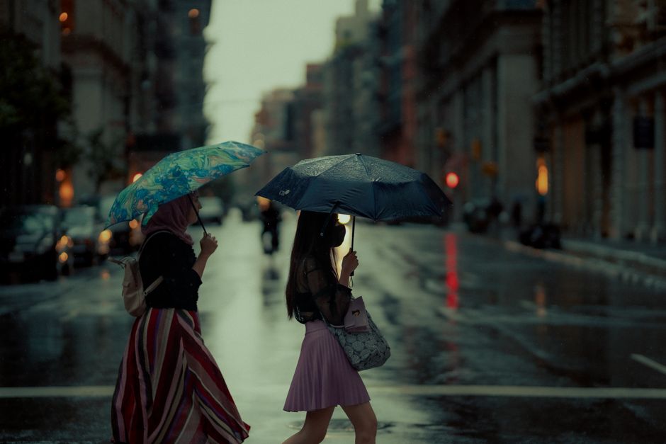 A rainy day in New York City with women crossing the street protected by umbrellas.
