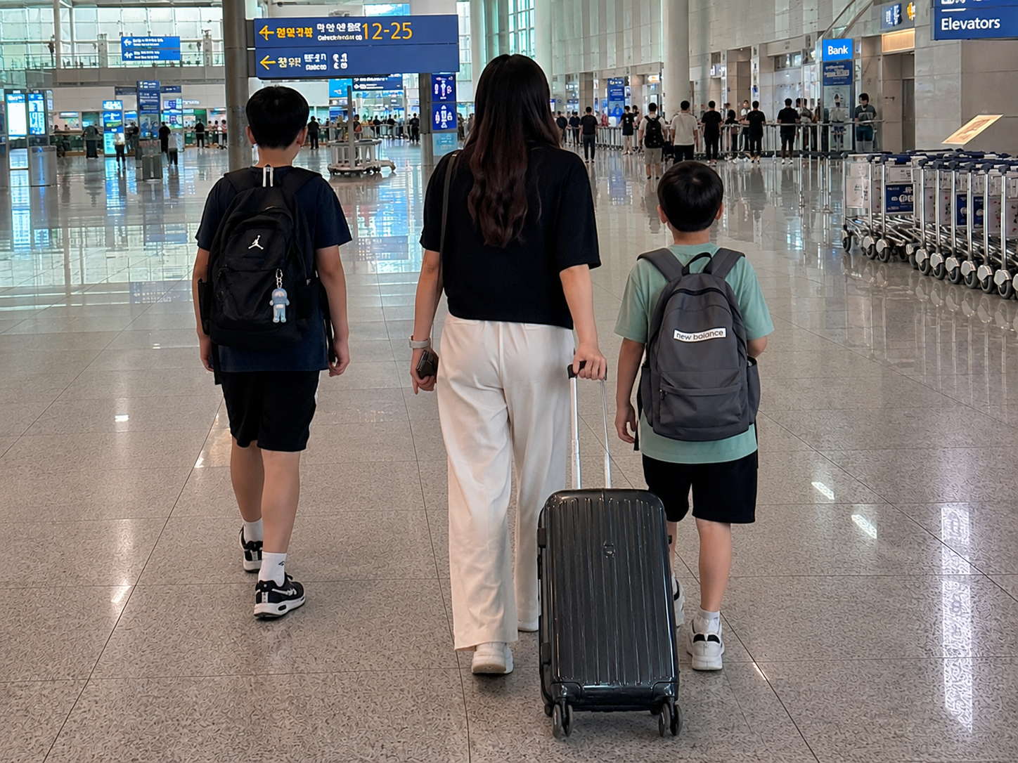 공항에서 미국으로 출발하기 위해 캐리어를 끄는 가족의 뒷모습