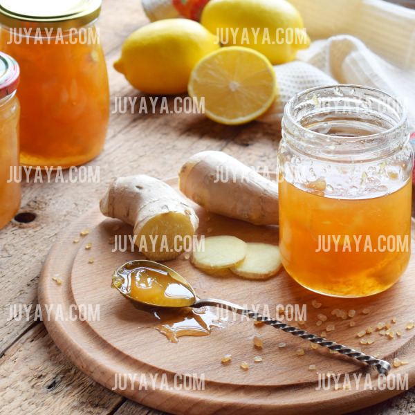 나무 도마 위에 생강 조각과 꿀이 듬뿍 담긴 작은 유리병이 놓여 있는 이미지. 홈메이드 건강 음료 준비를 위한 따뜻한 장면.