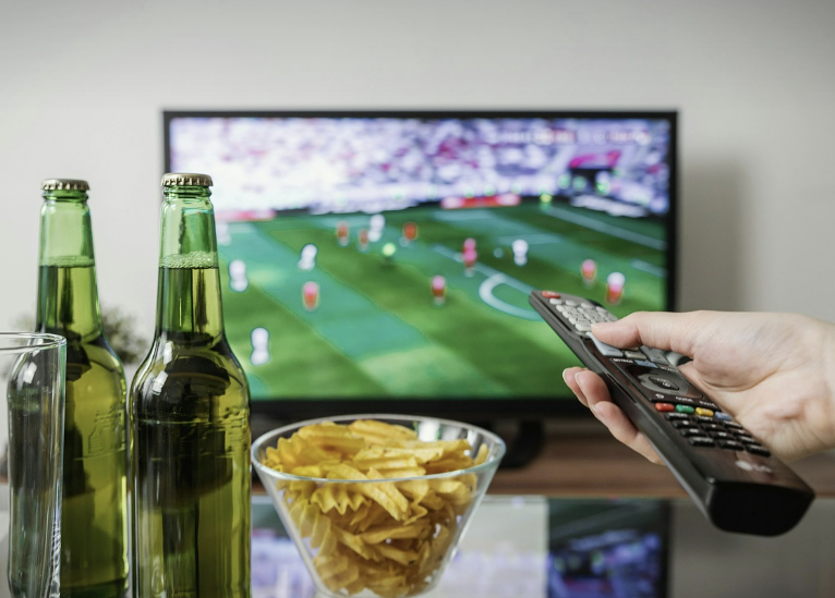 맥주와 감자칩을 보면서 스포츠 경기를 보고 있는 시청자