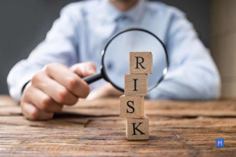 돋보기로 RISK 블록을 검토하는 모습, 불황기 재정 위험 분석과 신중한 재무 관리를 상징 via Canva