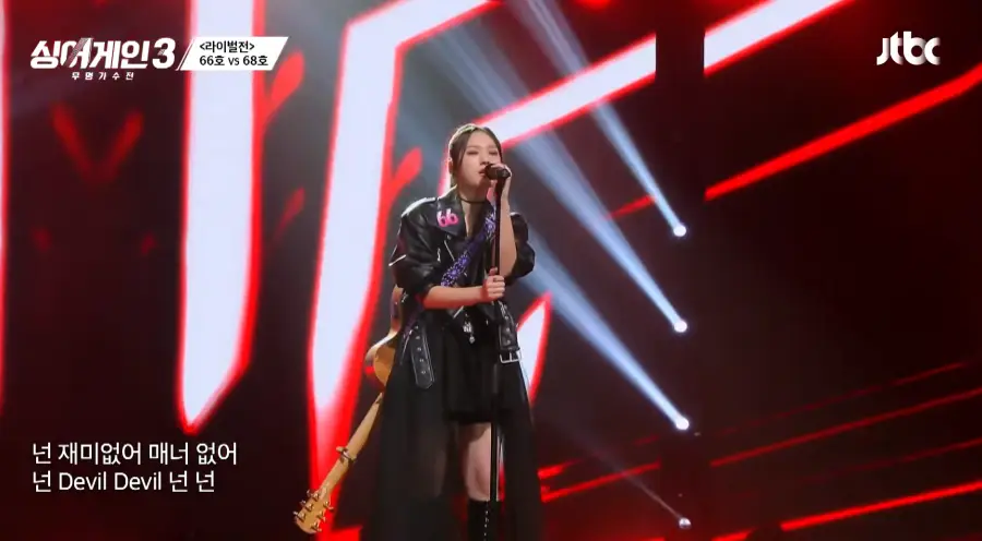 싱어게인3- 검은색 가죽자켓에 검은색 미니스커트 검은색 가죽부트를 신고 스탠딩마이크를 두손으로 잡고 기타를 뒤로맨채 노래하는 66호