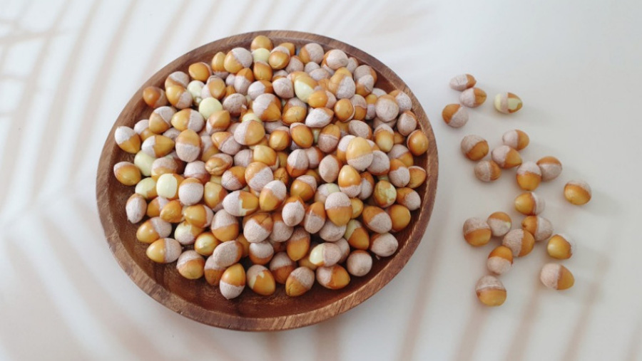 야생의 은행나무에서 채취를 한 열매인 은행을 껍질을 까서 속 알맹이만을 모아서, 하얀 바닥 위에 나무로 만든 동그란 그릇에 가득 담아두고, 그 옆의 바닥에도 몇 개 놓아둔 것을 찍은 사진